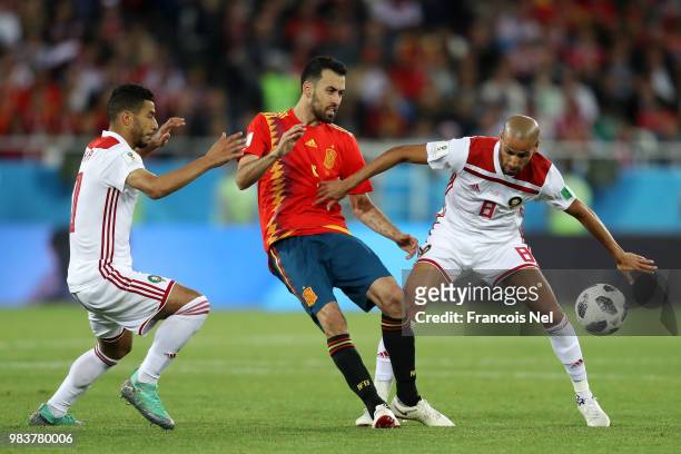 Sergio Busquets of Spain is challenged by Younes Belhanda of Morocco and Karim El Ahmadi of Morocco during the 2018 FIFA World Cup Russia group B...