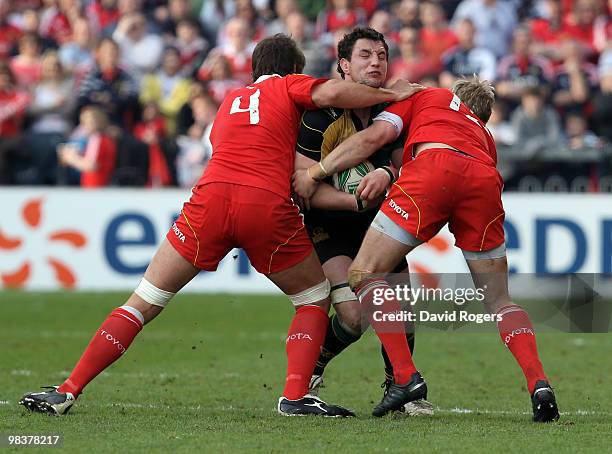 Phil Dowson of Northampton is tackled by Donncha O'Callaghan and Jean de Villiers during the Heineken Cup quarter final match between Munster and...