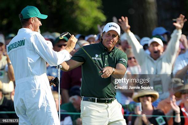 Phil Mickelson takes his putter from his caddie Jim Mackay on the 15th hole as a patron celebrates in the gallery during the third round of the 2010...