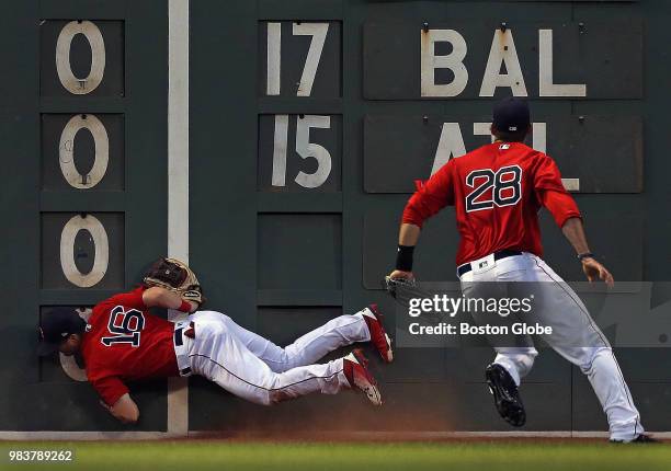 Boston Red Sox left fielder Andrew Benintendi collides with the Green Monster while attempting to make a play on an RBI double by Seattle Mariners...