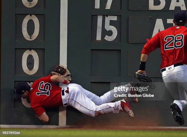 Boston Red Sox left fielder Andrew Benintendi collides with the Green Monster while attempting to make a play on an RBI double by Seattle Mariners...