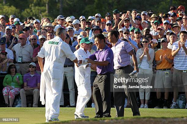 Tiger Woods shakes hands with caddie Andy Prodger while K.J. Choi of South Korea shakes hands with caddie Steve Williams after completing the third...