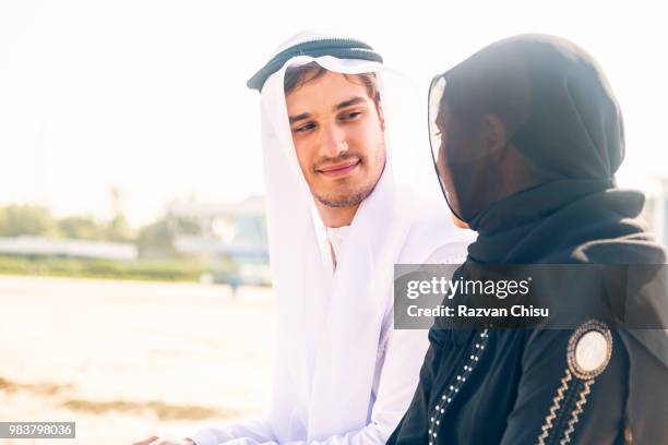 arabian couple sitting on the beach - agal stock pictures, royalty-free photos & images