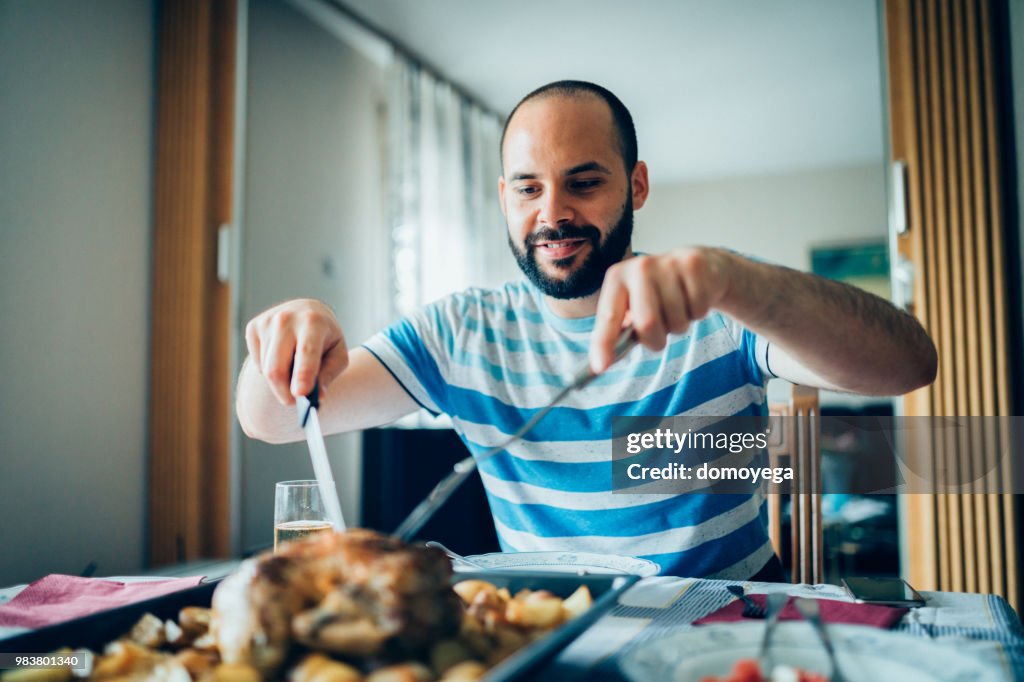 Young man is preparing to eat roast chicken at home