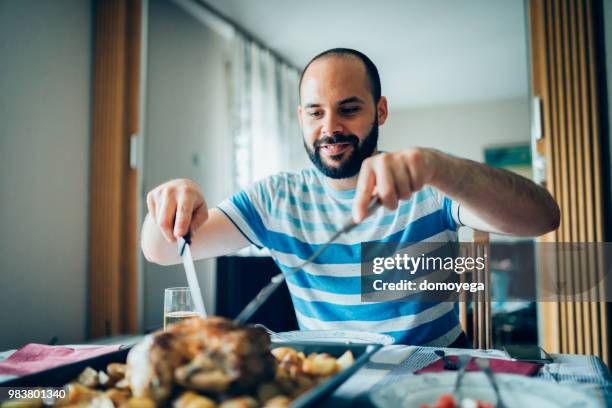 young man is preparing to eat roast chicken at home - single adults eating dinner at home stock pictures, royalty-free photos & images