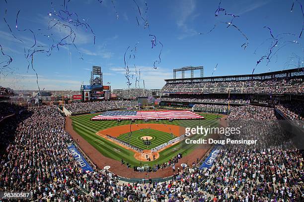 Players and fans observe the national anthem as the stars and stripes is presented by members of the US military as the Colorado Rockies host the San...