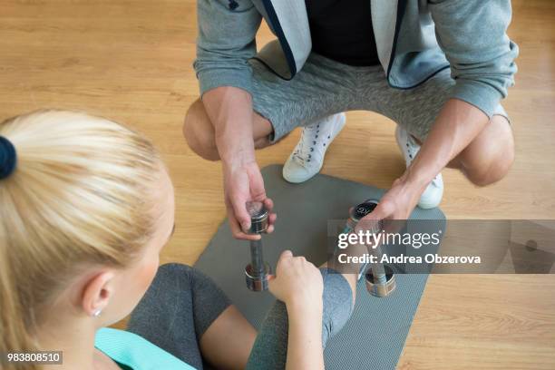 personal trainer handing dumbbells to young woman during workout session - segundo cuarto deportes fotografías e imágenes de stock