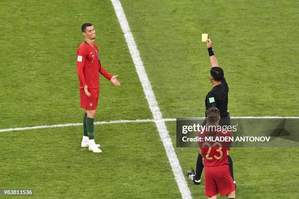 Paraguayan referee Enrique Caceres shows the yellow card to Portugal's forward Cristiano Ronaldo during the Russia 2018 World Cup Group B football...