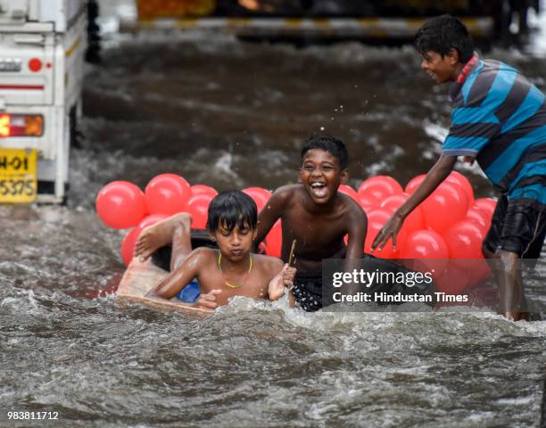 Children play on a water-logged street at King's Circle after heavy rains on June 25, 2018 in Mumbai, India. Heavy downpour led to waterlogging at...