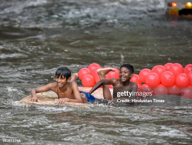 Children play on a water-logged street at King's Circle after heavy rains on June 25, 2018 in Mumbai, India. Heavy downpour led to waterlogging at...