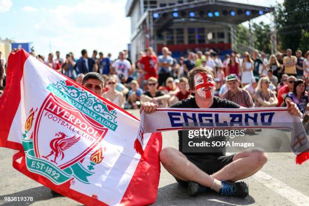 English fans seen sitting on the road with a Liverpool flag and a scarf in their hands.