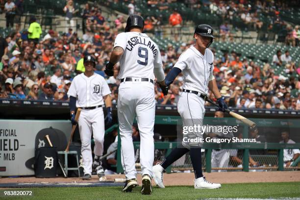 Nicholas Castellanos of the Detroit Tigers celebrates scoring a fourth inning run with Jose Iglesias while playing the Oakland Athletics at Comerica...