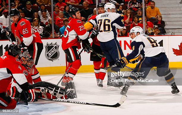 Derek Roy of the Buffalo Sabres shovels the puck in between a sprawling Chris Phillips and Pascal Leclaire of the Ottawa Senators for his 26th goal...