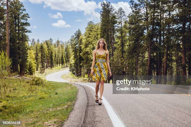 blonde walks towards you on road in forest kmphoto - kmphoto stock pictures, royalty-free photos & images