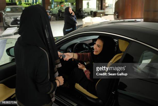 Modia Batterjee receives the keys to a Lexus car she is interested in buying from saleswoman Haifa Alsehli at a Lexus dealership the day after women...