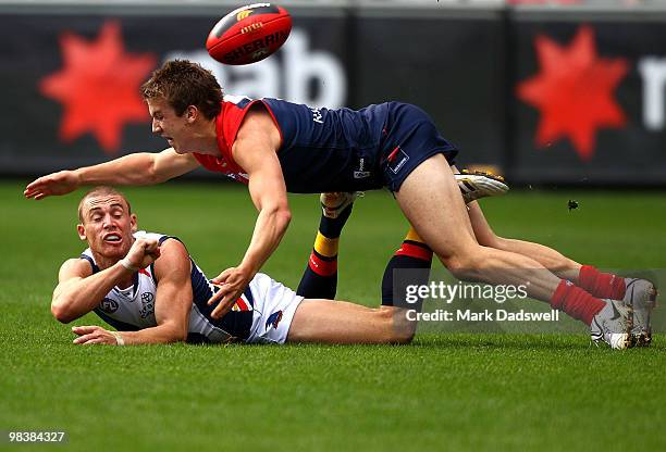 Simon Goodwin of the Crows handballs clear of Jack Trengrove of the Demons during the round three AFL match between the Melbourne Demons and the...