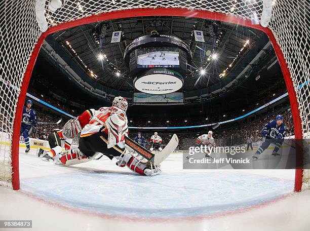 Henrik Sedin of the Vancouver Canucks looks on as Daniel Sedin of the Vancouver Canucks scores on Miikka Kiprusoff of the Calgary Flames during their...