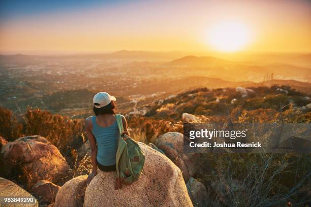 rear view of woman hiker sitting on rock on top of hill while looking at sunset over san diego... - rock hill stock pictures, royalty-free photos & images