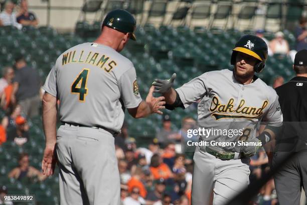 Jed Lowrie of the Oakland Athletics celebrates his ninth inning home run with third base coach Matt Williams while playing the Detroit Tigers at...