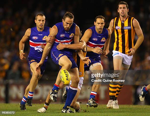 Ben Hudson of the Bulldogs kicks whilst being tackled during the round three AFL match between the Western Bulldogs and the Hawthorn Hawks at Etihad...