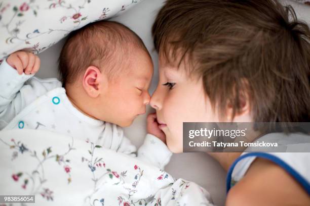 beautiful boy, hugging with tenderness and care his newborn bab - bab stock pictures, royalty-free photos & images