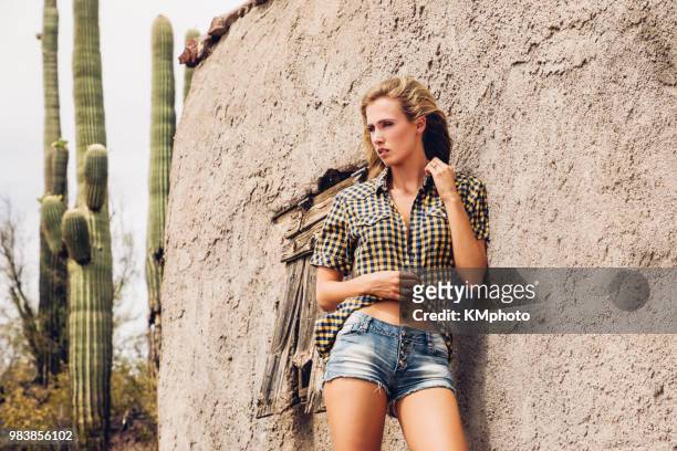 blonde girl against wall of desert house kmphoto - kmphoto stock pictures, royalty-free photos & images