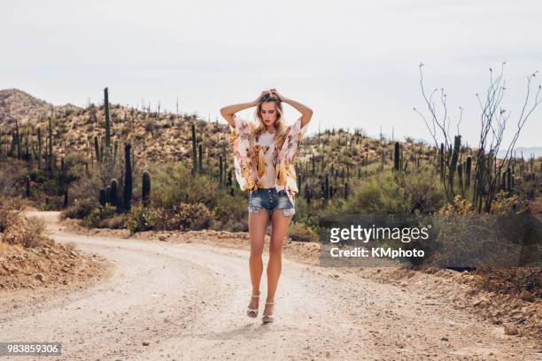 blonde girl w/ hands in hair on desertroad kmphoto - kmphoto stock pictures, royalty-free photos & images