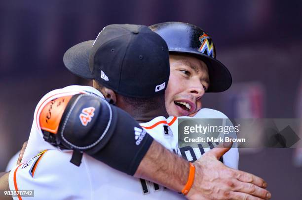 Justin Bour of the Miami Marlins hugs Cameron Maybin in the dugout after hitting a home run in the first inning during the game against the Arizona...