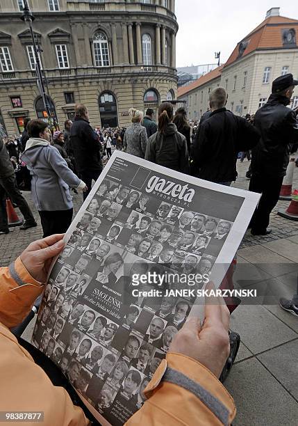 People collect free copies of a newspaper with the front page carrying a photograph of late president Lech Kaczynski and his wife Maria, along with...