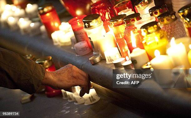 Man lights a candle during a church service for Polish president Lech Kaczynski in Berlin on April 11, 2010 the day after a plane carrying Polish...