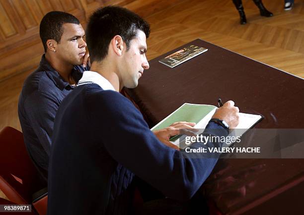 French Jo Wilfried Tsonga and serbian Novak Djokovic sign the guest book after a visit at the Oceanographic Museum in Monaco, on April 11 on the eve...