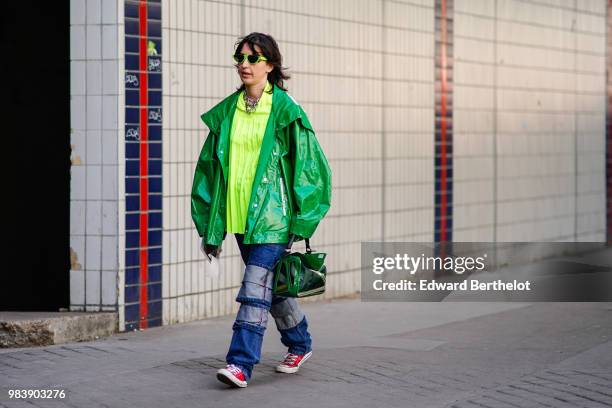 Guest wears a yellow top, a green pvc jacket, blue jeans, red sneakers, outside 1017 ALYX 9SM, during Paris Fashion Week - Menswear Spring-Summer...