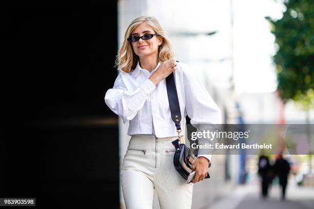 Xenia Adonts wears a white shirt, white pants, a Dior bag, sunglasses, outside 1017 ALYX 9SM, during Paris Fashion Week - Menswear Spring-Summer...