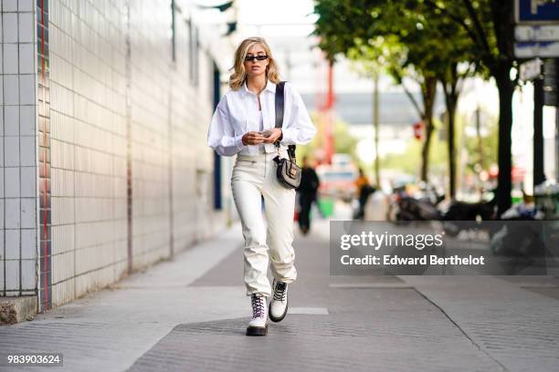 Xenia Adonts wears a white shirt, white pants, a Dior bag, sunglasses, outside 1017 ALYX 9SM, during Paris Fashion Week - Menswear Spring-Summer...