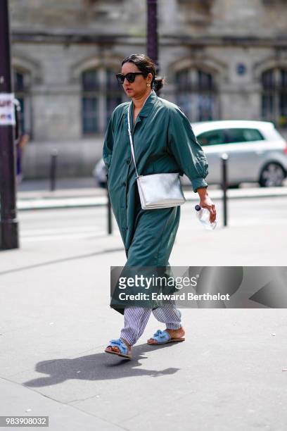 Guest wears a green coat, a silver bag, striped pants, sandals, outside Paul Smith, during Paris Fashion Week - Menswear Spring-Summer 2019, on June...