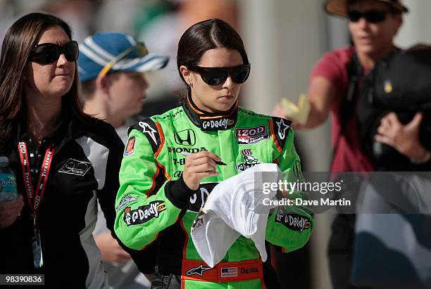 Danica Patrick, driver of the Team GoDaddy.com Dallara Honda, signs autographs for fans following the warm up period prior to the Indy Grand Prix of...