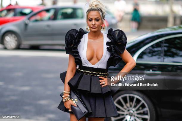 Ashley Hutson from "Red Hot Paris" wears a black and white low neck dress with ruffles, outside Balmain, during Paris Fashion Week - Menswear...