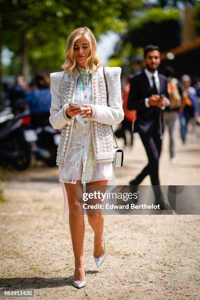 Xenia Adonts wears a white gliter tweed jacket with pearls, a white shiny dress, outside Balmain, during Paris Fashion Week - Menswear Spring-Summer...