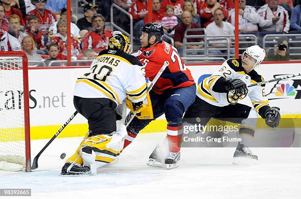 Jason Chimera of the Washington Capitals is pushed into Tim Thomas of the Boston Bruins by Jeffrey Penner at the Verizon Center on April 11, 2010 in...