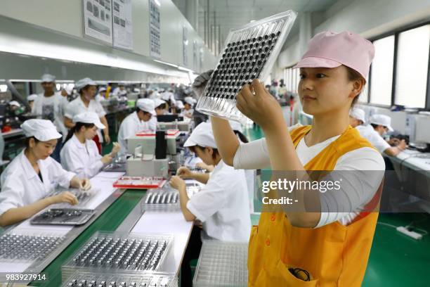 This photo taken on June 23, 2018 shows employees working on a micro motor production line at a factory in Huaibei in China's eastern Anhui province....