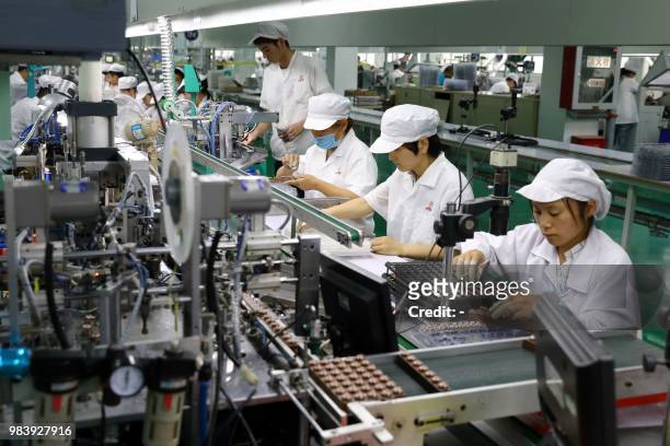 This photo taken on June 23, 2018 shows employees working on a micro motor production line at a factory in Huaibei in China's eastern Anhui province....