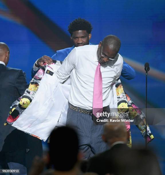 Sager Strong award winner Dikembe Mutombo accepts his jacket from Reggie Miller and Joel Embiid onstage at the 2018 NBA Awards at Barkar Hangar on...
