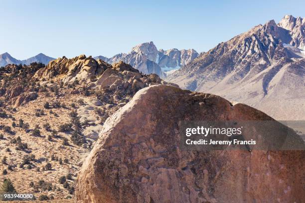 man rock climbs on huge granite boulder in the buttermilk area o - boulder rock stock-fotos und bilder