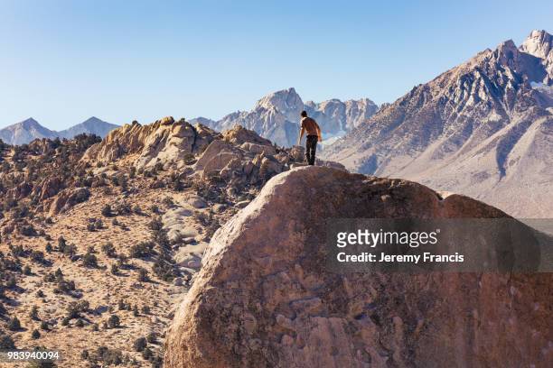 man rock climbs on huge granite boulder in the buttermilk area o - boulder rock stock-fotos und bilder