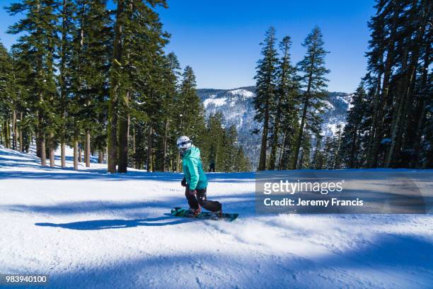 mixed race woman on snowboard rides quickly through snow in the - francis winter stock-fotos und bilder