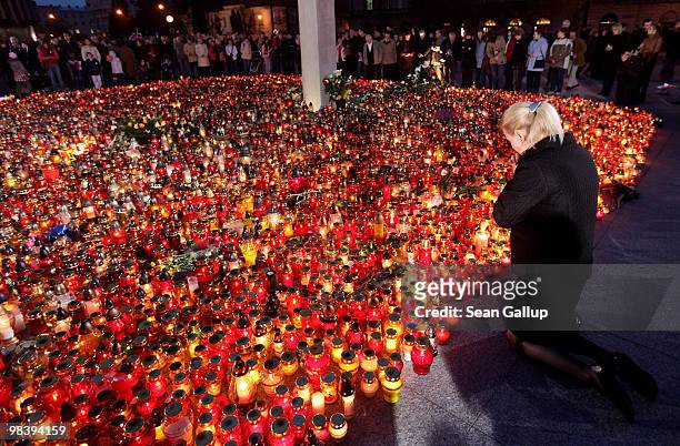 Young woman drops on her knees and prays over candles left by mourners at Pilsudski Square in memory of late Polish President Lech Kaczynski on April...