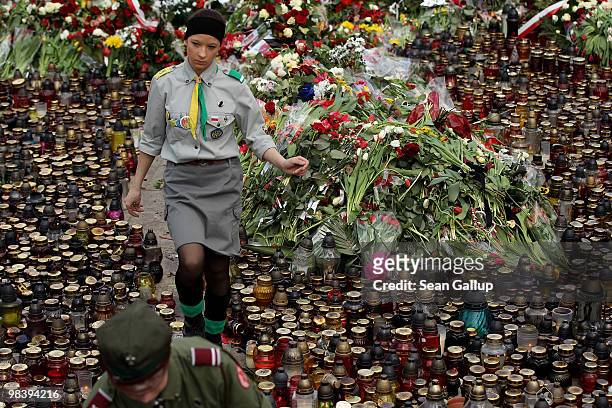 Polish girl scout and boy scout help to arrange candles and flowers left by mourners outside the Presidential Palace in memory of late Polish...