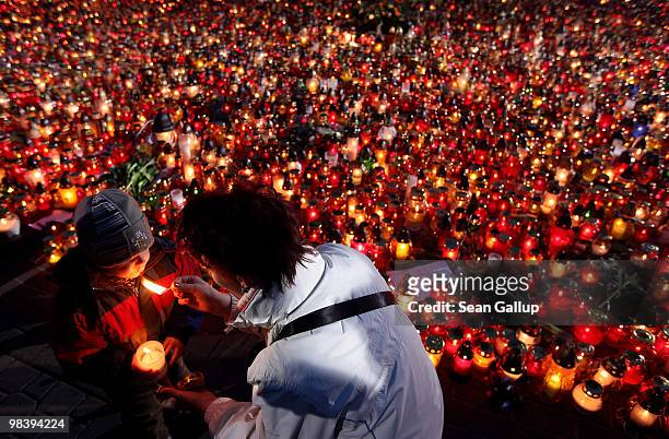 Mother and son light a candle to add it to thousands of others left by mourners at Pilsudski Square in memory of late Polish President Lech Kaczynski...