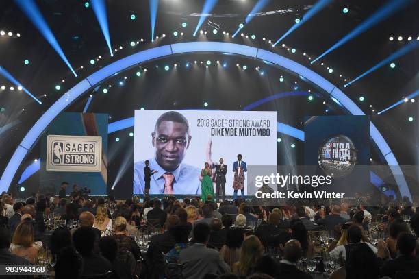 Sager Strong award winner Dikembe Mutombo accepts his jacket from Yvonne Orji, Reggie Miller, and Joel Embiid onstage at the 2018 NBA Awards at...