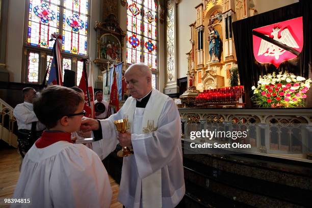 Priest gives communion to an altar boy during a memorial mass at Holy Trinity Church held in honor of Polish President Lech Kaczynski and the 96...